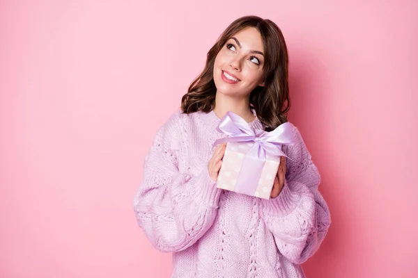 Foto de la mujer joven soñadora divertida suéter de punto obteniendo presente buscando espacio vacío aislado pastel rosa color fondo —  Fotos de Stock