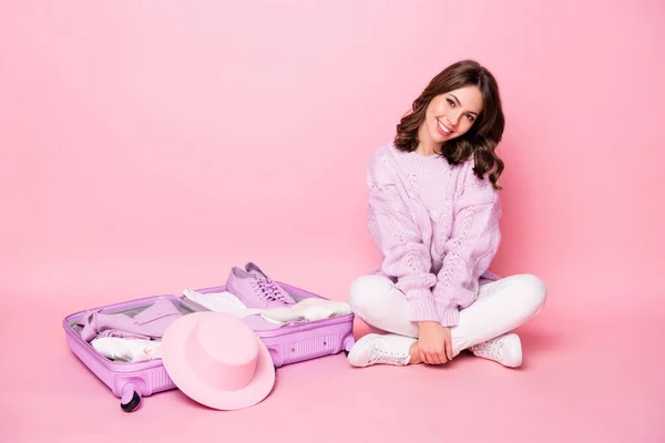 Retrato de tamaño completo de la persona bonita sentarse piso piernas cruzadas maleta abierta aislada sobre fondo de color rosa —  Fotos de Stock