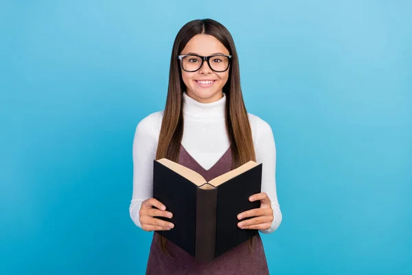 Foto da menina da escola jovem pupila eyewear ler materiais do livro lição de casa isolado sobre fundo de cor azul — Fotografia de Stock