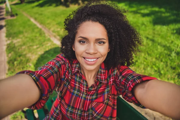 Foto mujer retrato sentado en el banco en el parque de la ciudad en primavera tomando selfie en la cámara sonriendo — Foto de Stock