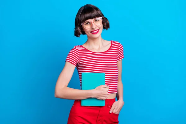 Gözlüklü fotoğrafçı kız gülümsüyor sınav için kitap hazırlıyor parlak mavi arkaplan — Stok fotoğraf