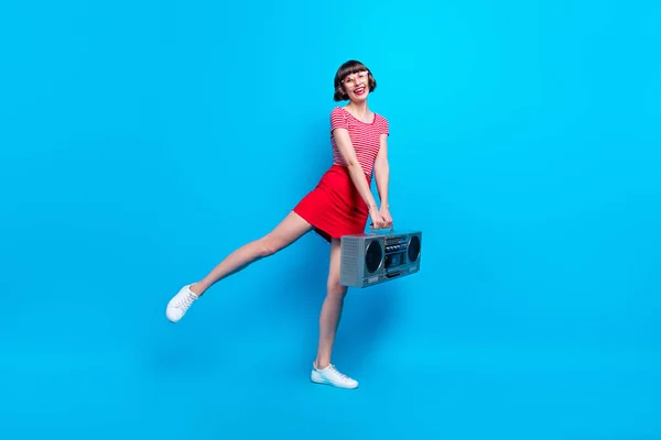 Фотография танцующей девушки в полный рост с ретро-магнитофоном на ярко-синем фоне — стоковое фото