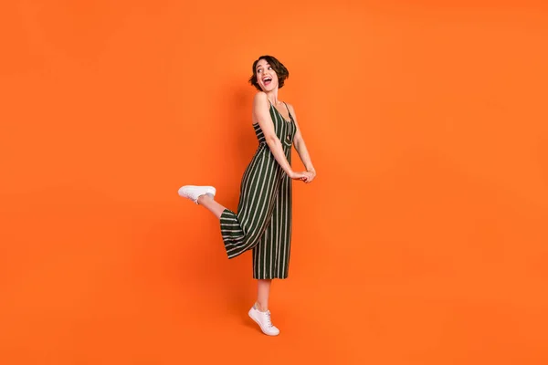 Foto lateral de perfil de longitud completa de la joven excitada sonrisa positiva feliz mirada espacio vacío aislado sobre fondo de color naranja — Foto de Stock