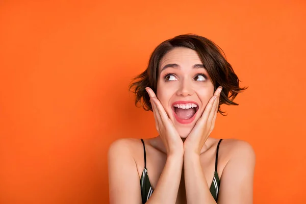 Fotografie mladé dívky ohromen překvapený omg wow šťastný pozitivní úsměv vypadají prázdné místo izolované přes oranžové barvy pozadí — Stock fotografie