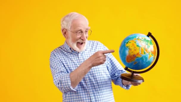 Güvenilir, neşeli yaşlı adam işaret parmağı küresini gösteriyor. — Stok video