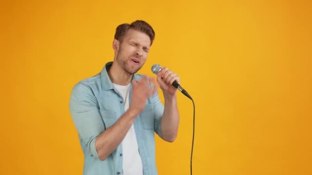 Безумный харизматичный позитивный рок-исполнитель держит песню с микрофоном — стоковое видео