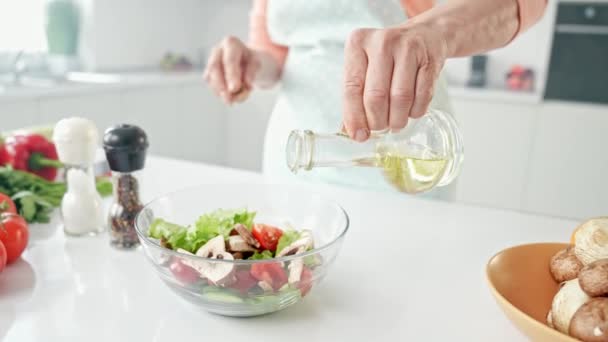 Alte Frauenhände halten Olivenölglas mit Gemüsesalat — Stockvideo