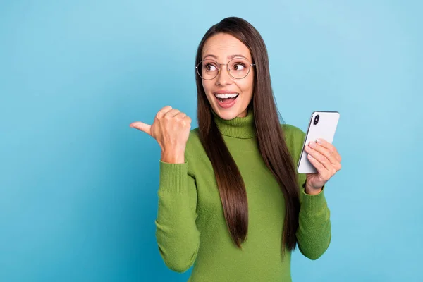 Foto de inteligente animado jovem mulher desgaste verde gola alta óculos comunicando moderno dispositivo sorrindo isolado azul cor de fundo — Fotografia de Stock