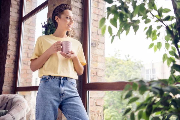 Фото молодой счастливой красивой красивой женщины смотреть окно выходные держать чашку улыбки в помещении дома — стоковое фото