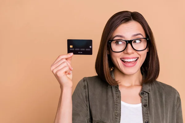 Fénykép a kíváncsi vicces hölgy bemutató műanyag betéti kártya viseljen szemüveget khaki ing elszigetelt bézs színű háttér — Stock Fotó