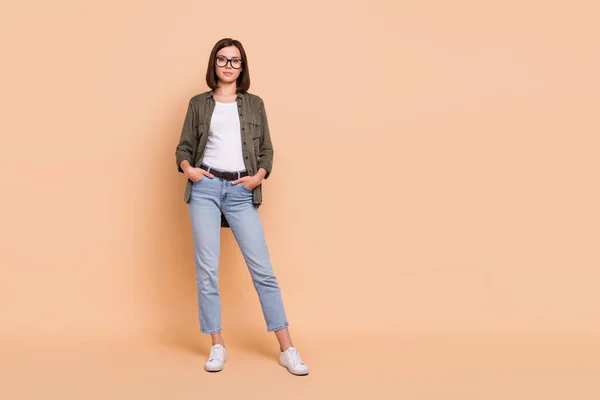 Foto de confiança bem sucedida senhora de negócios mãos bolsos usar especificações calças jeans camisa cáqui isolado cor bege fundo — Fotografia de Stock