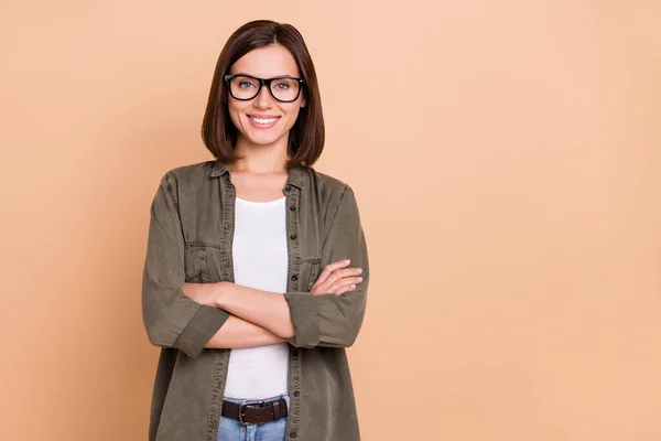 Fénykép a magabiztos szabadúszó hölgy keresztbe karok visel szemüveg khaki ing elszigetelt bézs színű háttér — Stock Fotó