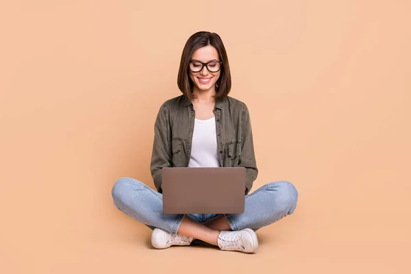 거실에 앉아 있는 밝고 긍정적 인 프로그래머의 사진 pc 착용 목격자 khaki 셔츠외진 베이지 색 배경 — 스톡 사진
