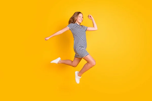 Foto de perfil em tamanho completo de menina alegre despreocupada correndo olhar espaço vazio isolado no fundo de cor amarela — Fotografia de Stock