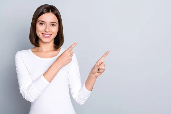 Foto van mooie bob hairdo millennial dame tonen lege ruimte dragen witte shirt geïsoleerd op grijze achtergrond — Stockfoto