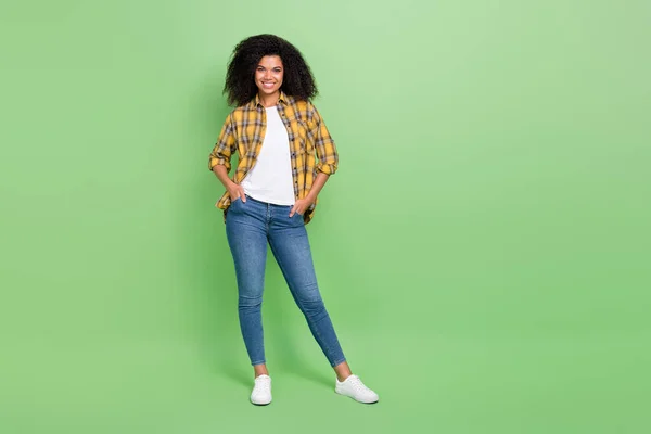 Foto em tamanho completo de boa morena jovem senhora stand desgaste camisa amarela jeans tênis isolado no fundo de cor verde — Fotografia de Stock