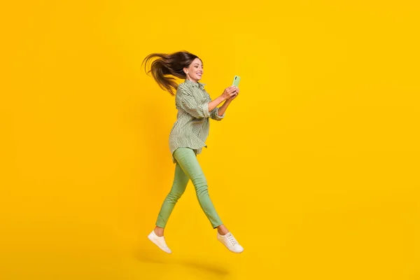 Full kropp profil sida foto av ung kvinna använda smartphone app ladda ner hoppa promenad isolerad över gul färg bakgrund — Stockfoto
