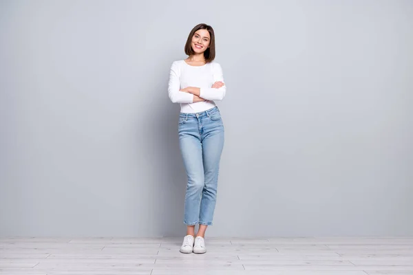 Foto de adorable joven brillante vestida con ropa blanca brazos sonrientes plegados caminando aislado de hormigón gris fondo de la pared — Foto de Stock