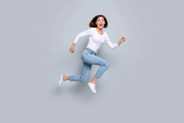 Zdjęcie słodkie słodkie młoda kobieta nosić biały strój skoków wysoki bieg szybko uśmiechnięty odizolowany szary kolor tła — Zdjęcie stockowe