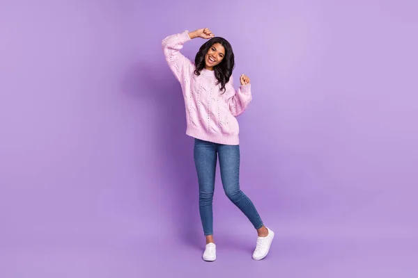 Foto de brillante linda mujer de piel oscura usar suéter rosa sonriendo bailando levantando puños aislados color violeta fondo —  Fotos de Stock