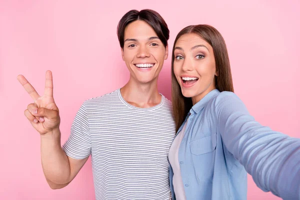 Photo of shocked sweet young couple wear casual clothes smiling recording self video showing v-sign isolated pink color background — Stock Photo, Image