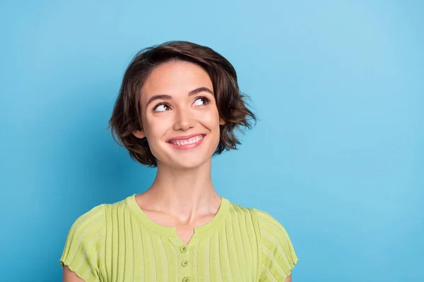 Foto de dulce dama joven reflexiva usar camiseta verde sonriendo buscando espacio vacío aislado color azul fondo —  Fotos de Stock