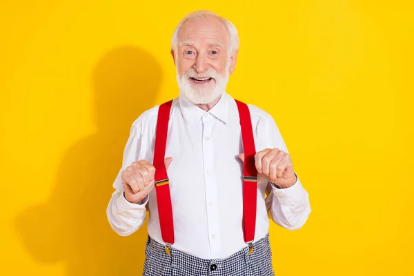 Yakışıklı yaşlı adamın fotoğrafı beyaz gömlek giyer kırmızı pantolon askısı sarı arka planda izole edilir. — Stok fotoğraf