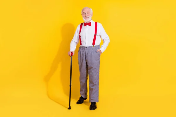 Sopalı, havalı, yaşlı bir adamın tam vücut fotoğrafı kravat, pantolon askısı, ekose pantolon, sarı arka planda izole edilmiş ayakkabılar. — Stok fotoğraf