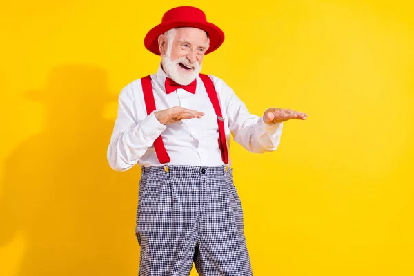 Fotografie pána stařec tanec oblečení červená čepice kravata košile šle kalhoty izolované na žlutém pozadí — Stock fotografie