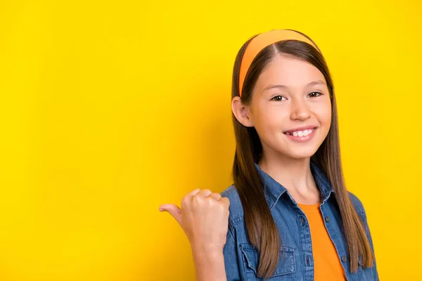 Fotografie rozkošný pěkný preteen dívka oblečená džíny košile ukazující palec nahoru zpět prázdný prostor s úsměvem izolované žluté barvy pozadí — Stock fotografie
