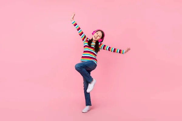 Foto de inspirada despreocupada linda dama pequeña danza usar auriculares camisa a rayas jeans aislado color rosa fondo — Foto de Stock