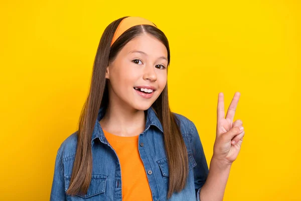 Φωτογραφία από γοητευτικό funky preteen κορίτσι ντυμένος τζιν πουκάμισο δείχνει v-σημάδι χαμογελώντας απομονωμένο κίτρινο χρώμα φόντο — Φωτογραφία Αρχείου