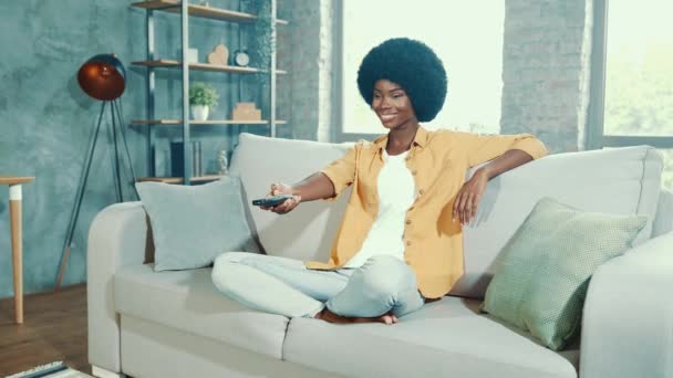 Милая мечтательная расслабленная леди сидит диван переключатель телеканала пульт дистанционного управления — стоковое видео