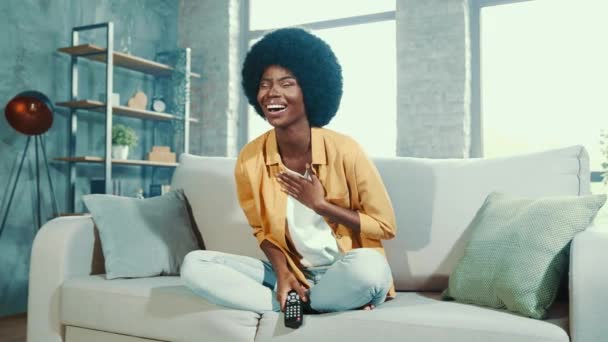 Позитивна весела леді сидить на домашньому дивані насолоджуйтесь комедійною драмою на вихідні — стокове відео