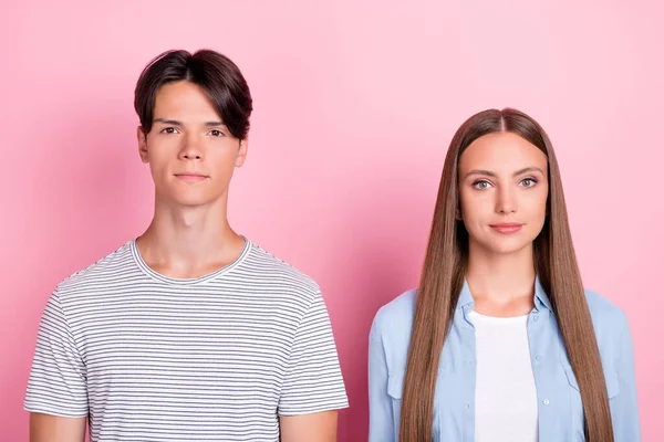 Foto de serios amantes jóvenes seguros vestidos trajes casuales aislados de color rosa de fondo —  Fotos de Stock