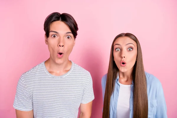 Foto de chocado animado jovem casal usar roupas casuais grandes olhos isolado cor-de-rosa fundo — Fotografia de Stock