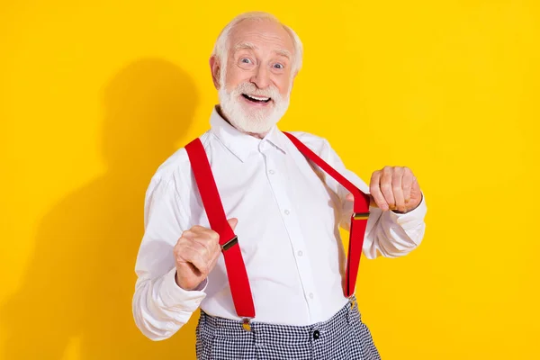Foto de engraçado homem mais velho mostrar olhar desgaste camisa branca suspensórios vermelhos isolados no fundo de cor amarela — Fotografia de Stock