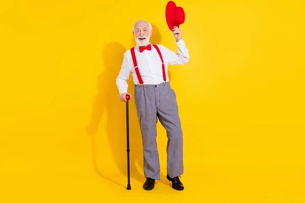Foto de tamaño completo de hombre viejo suave fresco usar corbata camisa blanca tirantes rojos pantalones de cuadros zapatos aislados en el fondo de color amarillo —  Fotos de Stock