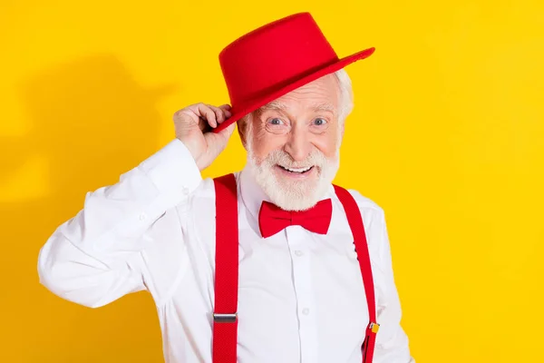 Havalı, yaşlı bir adamın fotoğrafı. Kırmızı şapkalı, kravatlı, pantolon askılı, sarı arka planda. — Stok fotoğraf
