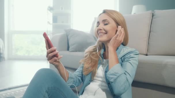 Eğlenceli bir bayan haftasonunu kulaklık takarak, telefon çalma listesini dinleyerek geçirir. — Stok video