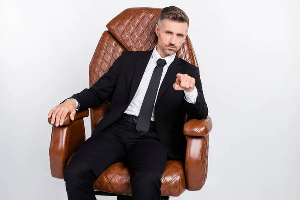Φωτογραφία από σίγουρη σοβαρή ώριμη εργαζόμενος ντυμένος μαύρο κοστούμι κάθεται άνετα δερμάτινη καρέκλα δείχνοντας δάχτυλο που απομονώνονται γκρι φόντο χρώμα — Φωτογραφία Αρχείου
