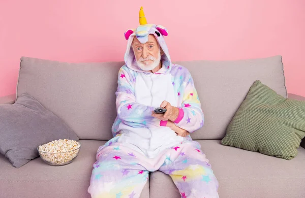Porträt eines attraktiven, gelangweilten, grauhaarigen Mannes, der auf einem Sofa sitzt und sich Videoserien isoliert über rosa Hintergrund ansieht — Stockfoto