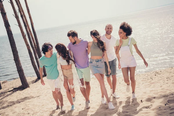 Foto de cuerpo completo de jóvenes amigos alegres ir a pie paso mar costa océano relajarse sol al aire libre —  Fotos de Stock