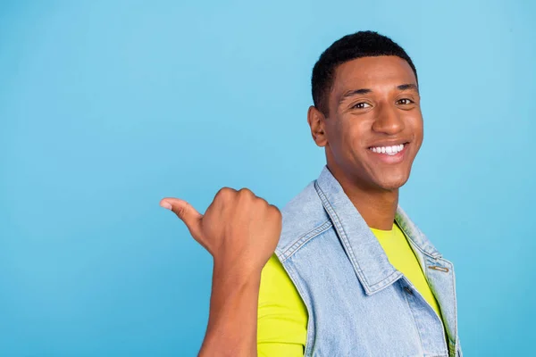 Foto del lado del perfil de hombre joven afro punto pulgar espacio vacío aconsejar seleccionar descuento aislado sobre fondo de color azul — Foto de Stock