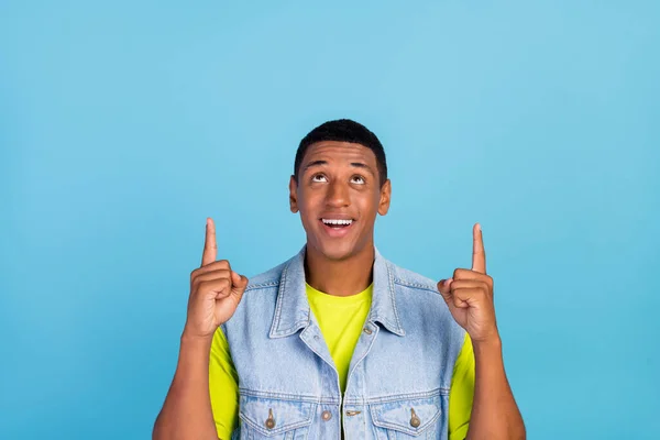Foto de mirada de hombre africano joven indican dedos vacíos promoción del espacio sugieren aislado sobre fondo de color azul —  Fotos de Stock