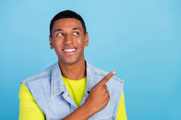 Foto von jungen Afro-Mann neugierig Blick zeigen Finger leeren Raum beraten Promo isoliert über blauen Farbhintergrund — Stockfoto