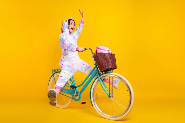 Lunghezza completa corpo formato foto donna in costume in sella bicicletta mano ondulante isolato luminoso colore giallo sfondo — Foto Stock