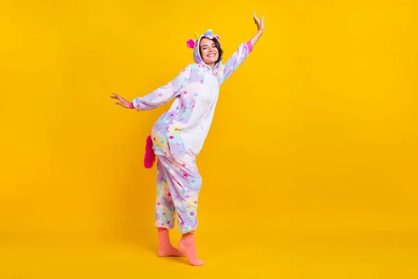 Full length photo of cheerful happy positive young woman raise hands wear unicorn pajama isolated on yellow color background — Stock Photo, Image