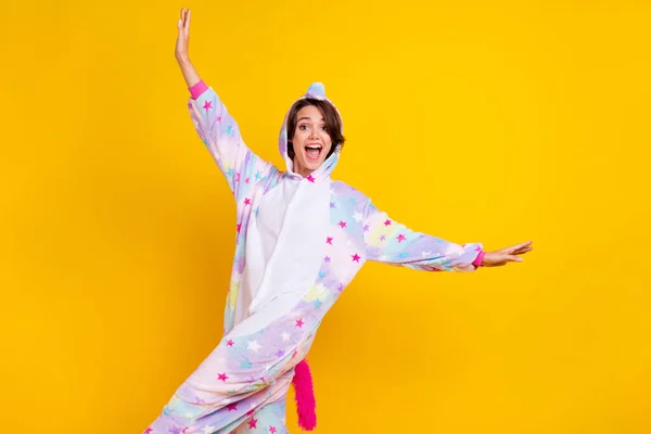 Photo portrait woman in unicorn costume dancing overjoyed on pajama party isolated vibrant yellow color background — Stock Photo, Image