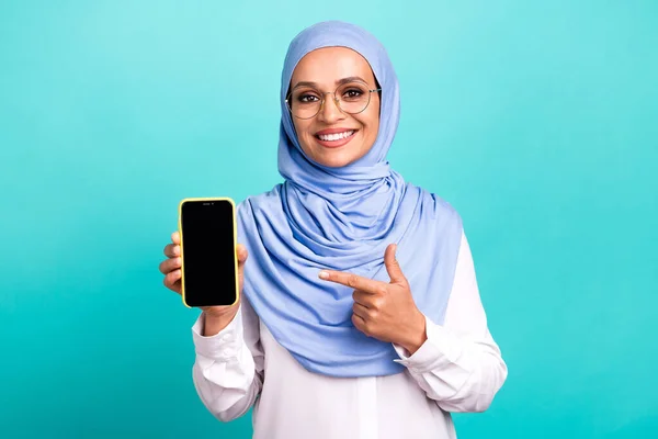 かわいいかなり若い女性の写真は、アラブのスカーフの眼鏡を着用ポイントモダンなガジェット空のスペース隔離されたターコイズ色の背景 — ストック写真